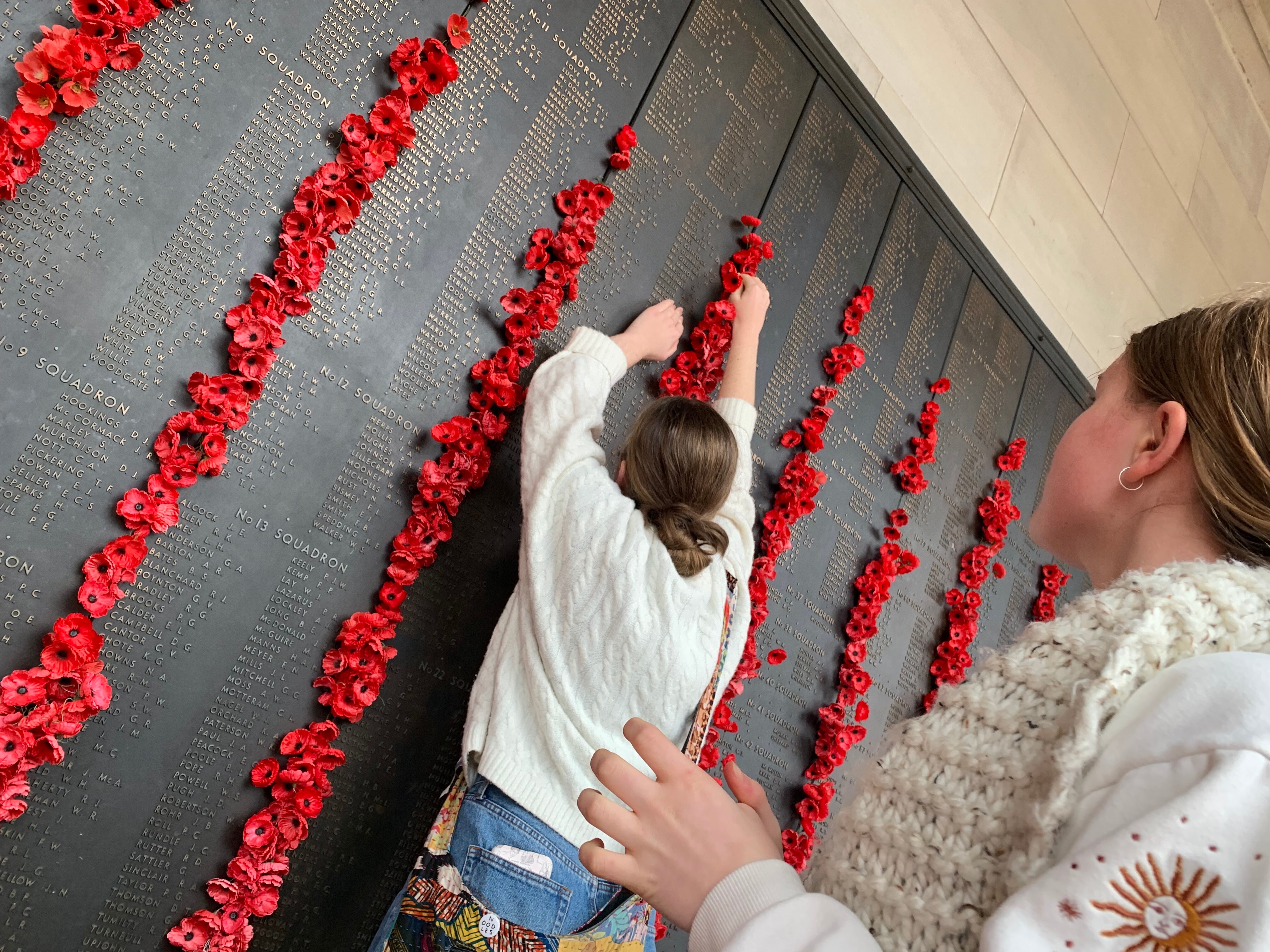 A granddaughter places a poppy next to her great grandfather's name on the Roll of Honour at the Australian War Memorial.