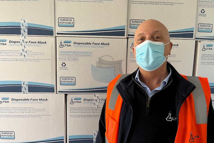 Ray Harris stands in front of boxes of surgical face masks