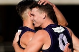 Two Fremantle players smile as they hug each other