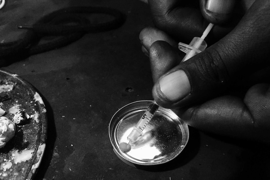 A powdered drug is drawn off a metal plate into a syringe.