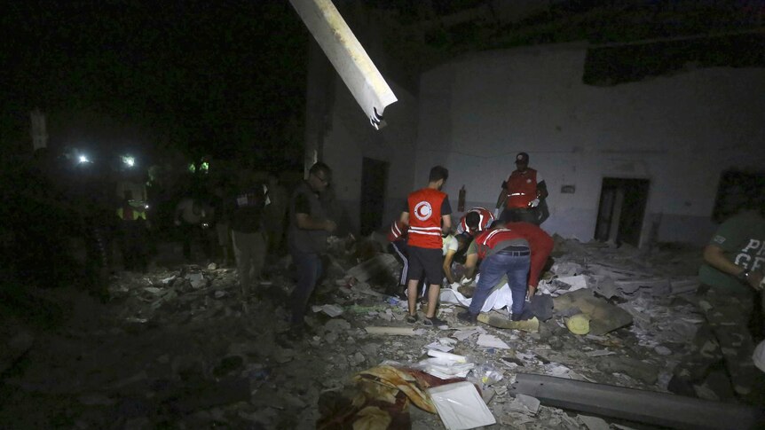 Libyan Red Crescent workers recover migrants bodies after an airstrike at a detention centre.