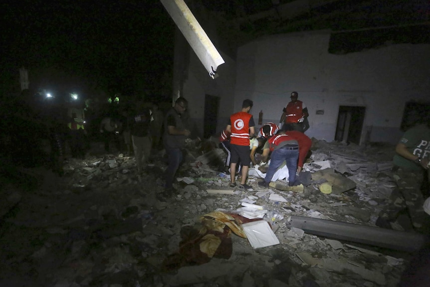 Libyan Red Crescent workers recover migrants bodies after an airstrike at a detention centre.