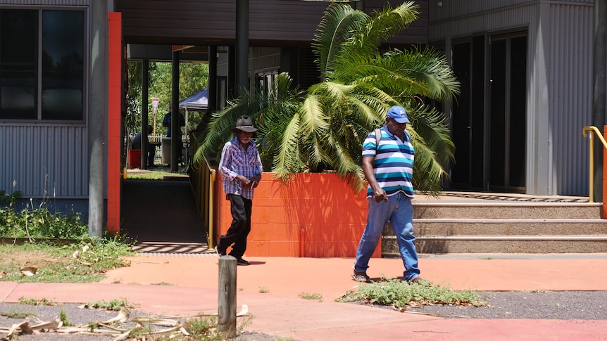 Two Aboriginal men walk away from a building.