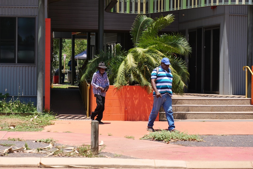 two aboriginal men leave a building