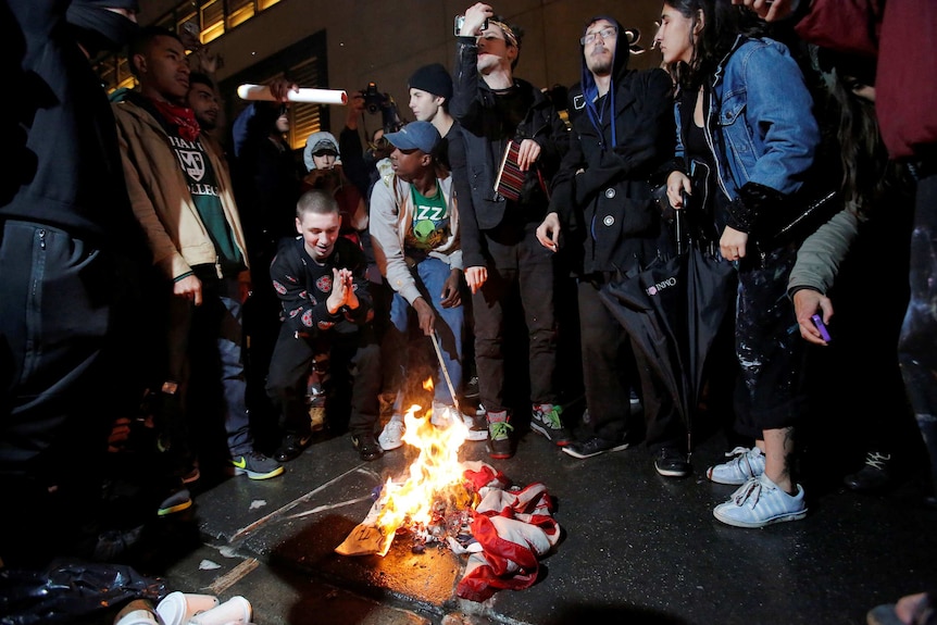 Protesters burn a US flag outside Trump Tower following President-elect Donald Trump's election.
