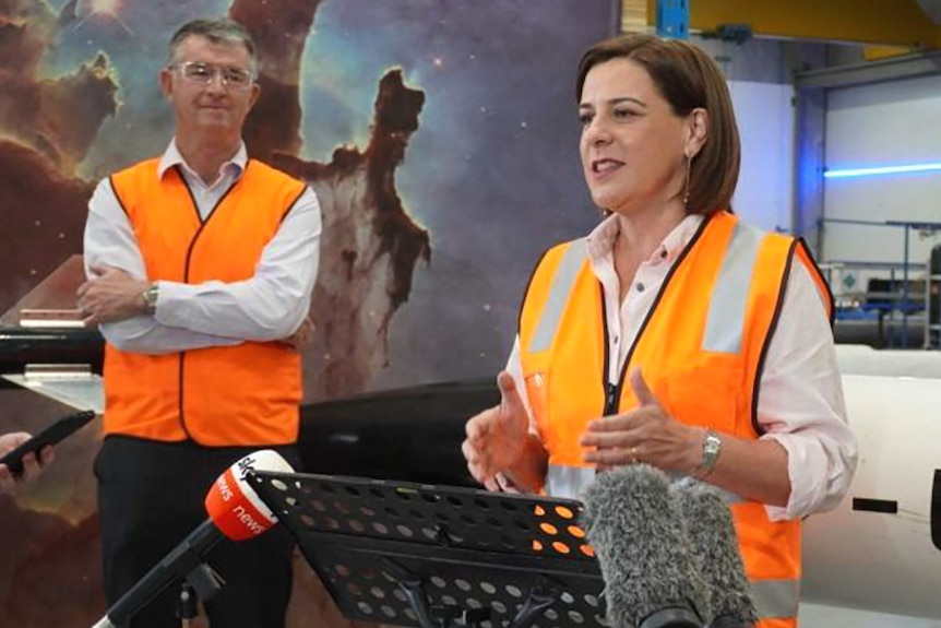 LNP leader Deb Frecklington in high-vis speaking to the media, watched by her deputy Tim Mander