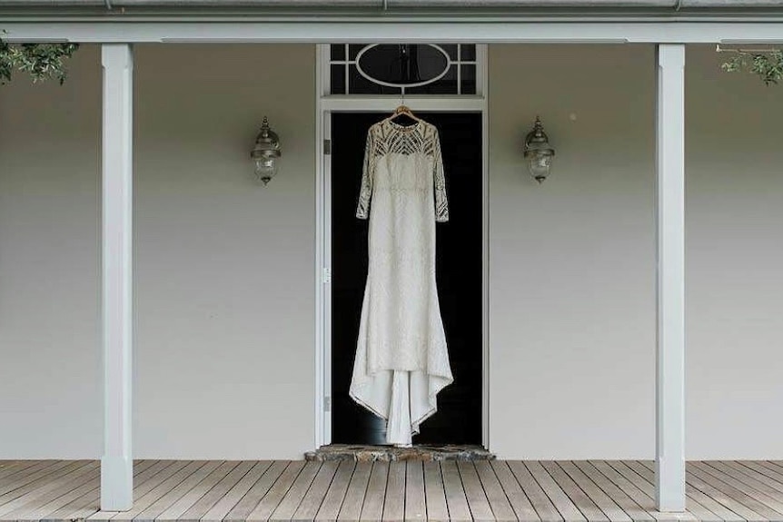 A wedding dress hangs in a doorway on a verandah
