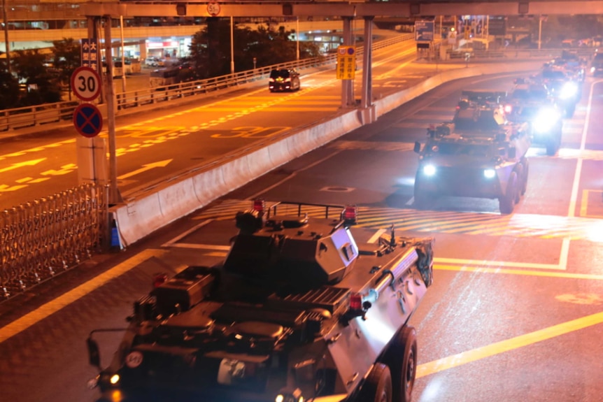Armored personnel carriers of China's People's Liberation Army drive down a highway.