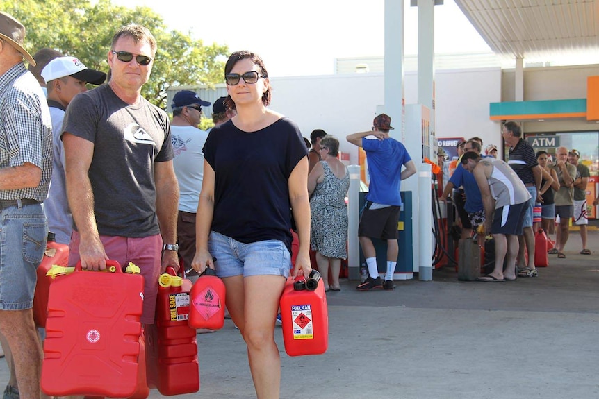 Mark and Melissa Mitchell queue at the only functioning petrol station in Rockhampton