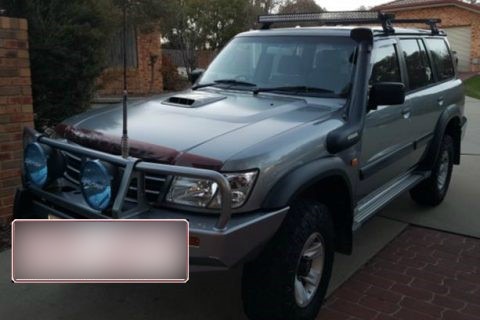 A dark grey Nissan patrol pictured in a driveway, with a blurred licence plate.