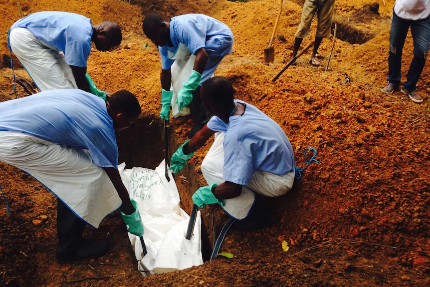 The wrapped corpse of an an Ebola victim is lowered into a grave in Kailahun, Sierra Leone.