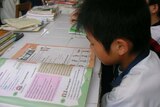 A young Chinese boy reads a textbook with English characters.