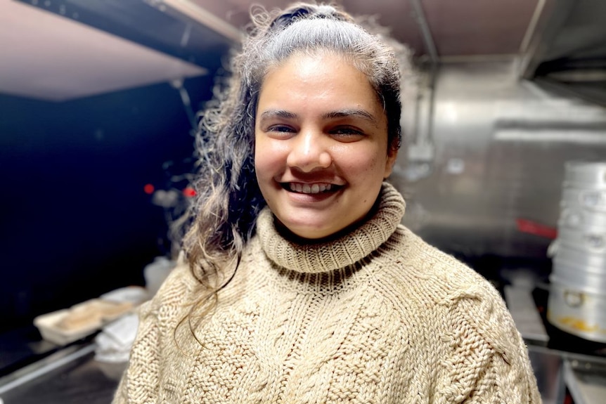 A woman in a cream sweater smiles for the camera.