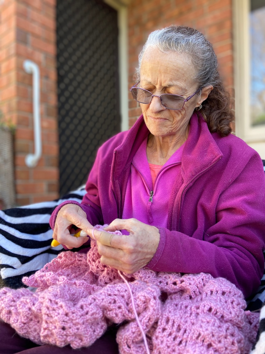 Wendy Morgan sits outside her apartment doing crochet.