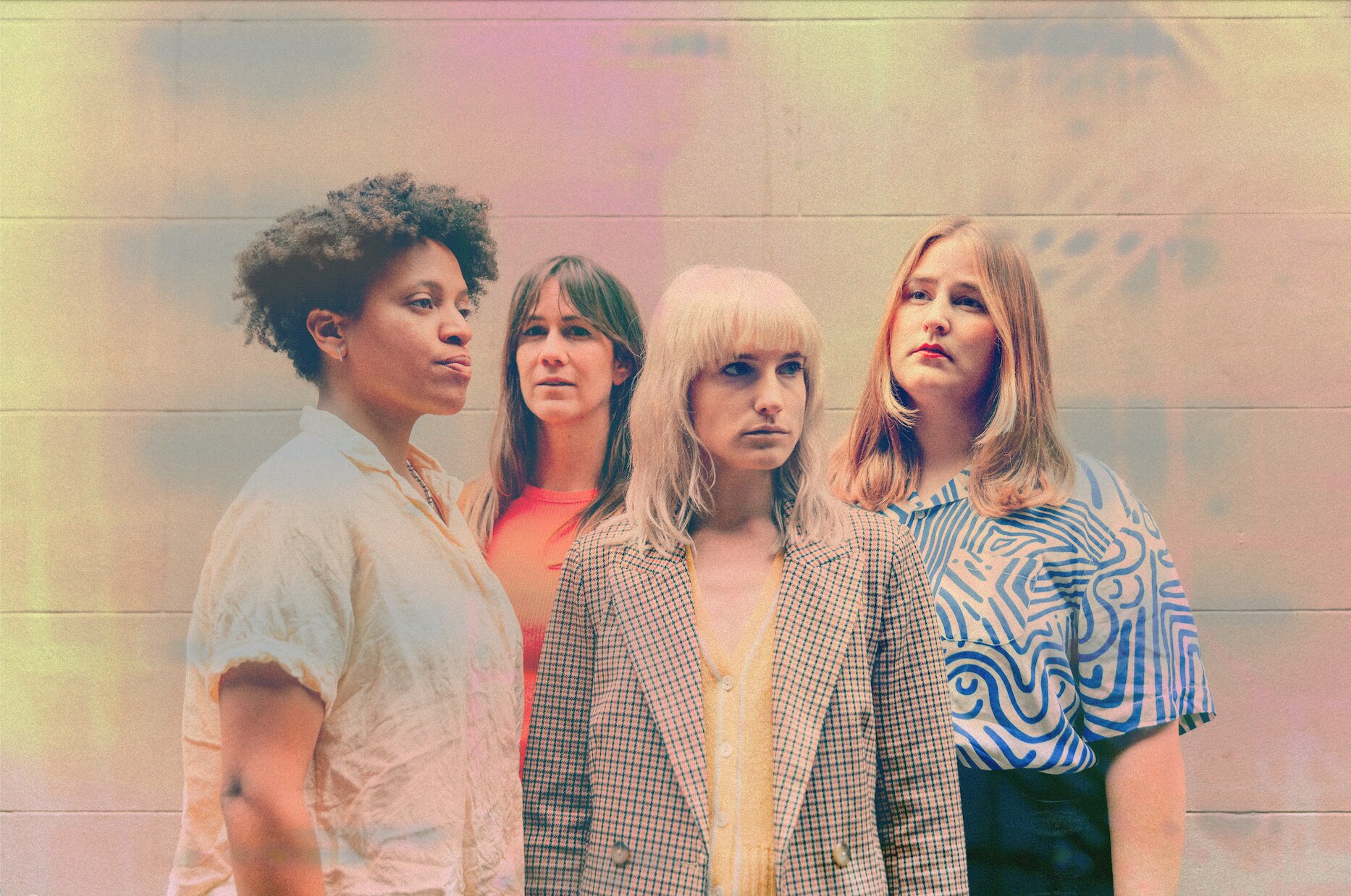A photo of four feminine-presenting people against a concrete wall with a pastel washed filter over the top