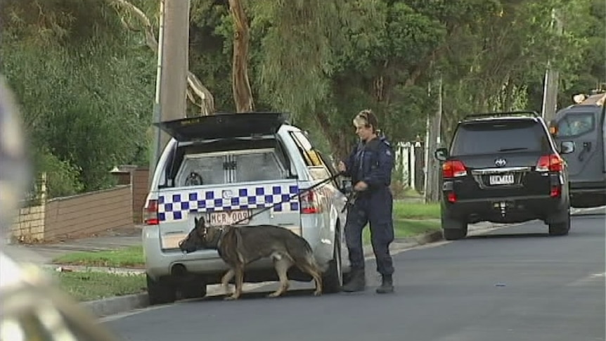 Police officer and dog outside siege house