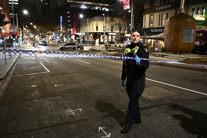 A police officer stands behind police tape at the scene of a crash in Melbourne's CBD