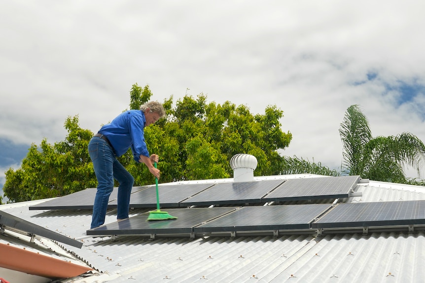 Grant Howard on his roof in Mackay cleaning solar panels, November 2021.