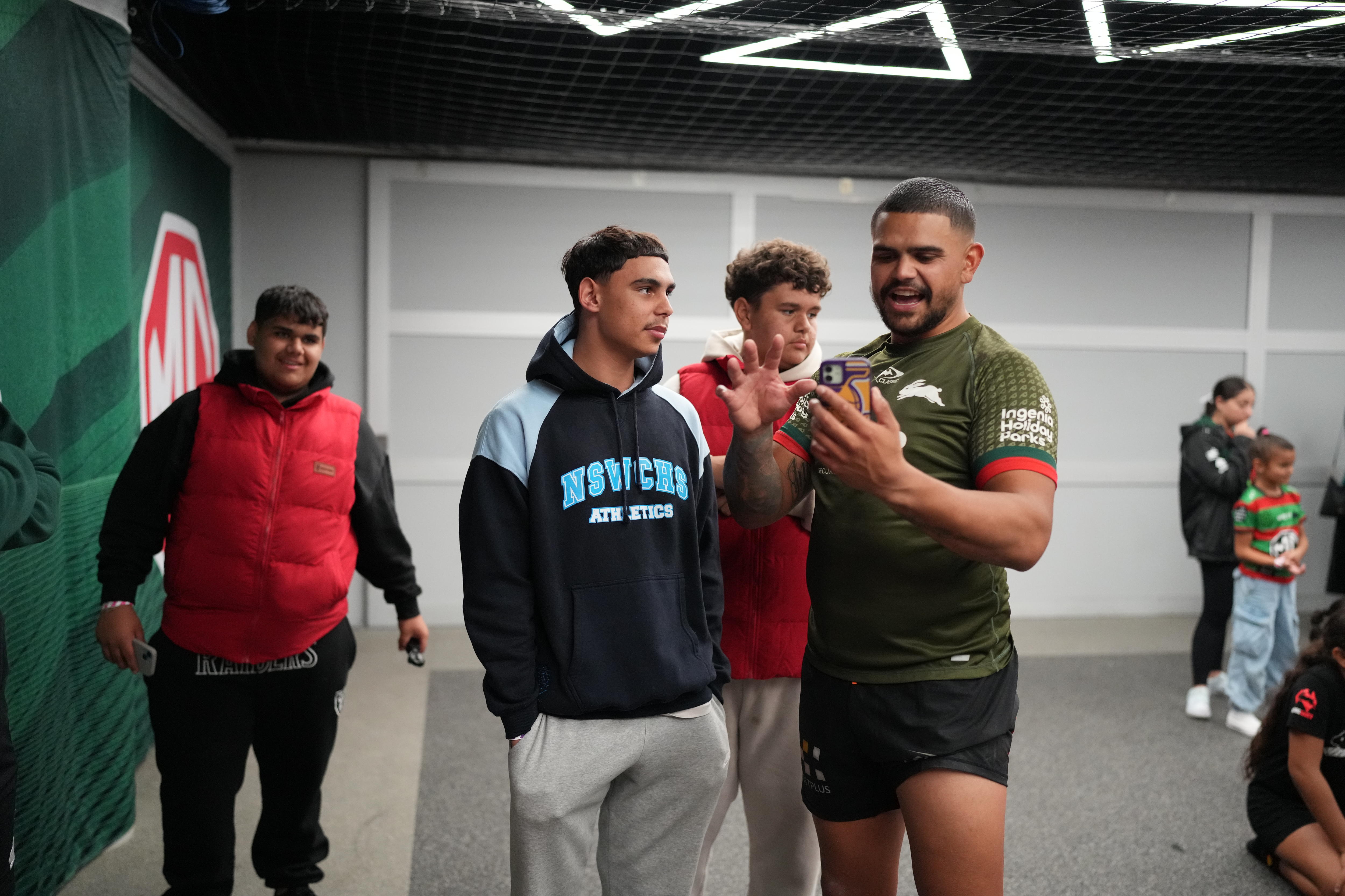 Latrell Mitchell com a camisa dos Rabbitohs conversando com as crianças, uma atrás vestindo uma camisa dos Bunnies