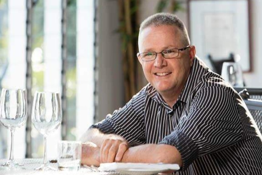 Darwin restaurant Pee Wees at The Point owner Simon Matthews sitting at a restaurant table with wine glasses