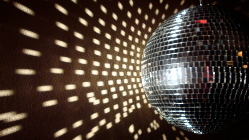 The close up of a silver disco ball shines light out.