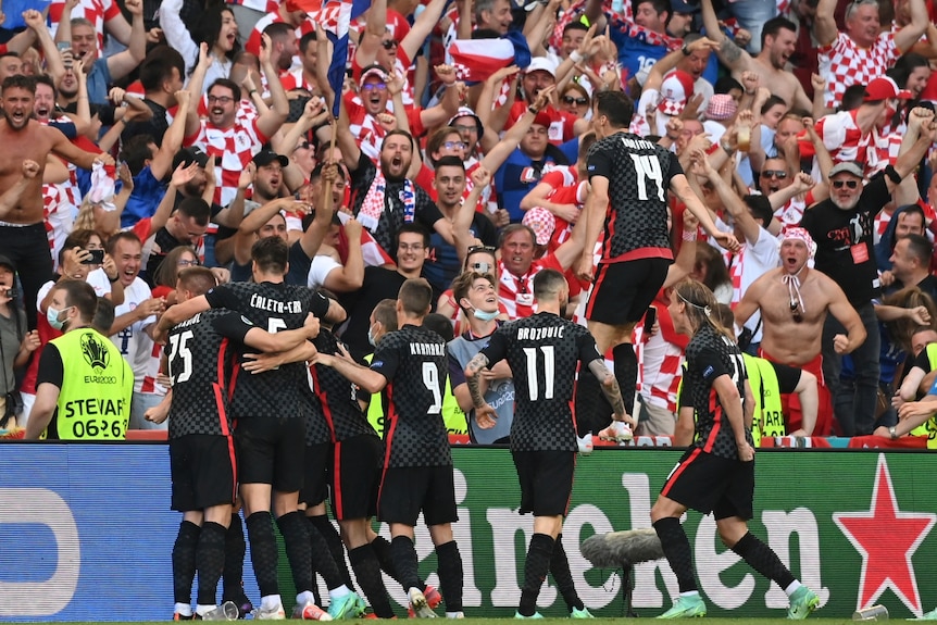 Los jugadores croatas celebran frente a los aficionados vestidos de rojo y blanco con vítores y sonrisas