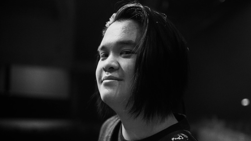 Black and white photo of Polaris guitarist Ryan Siew looking at the camera and smiling.