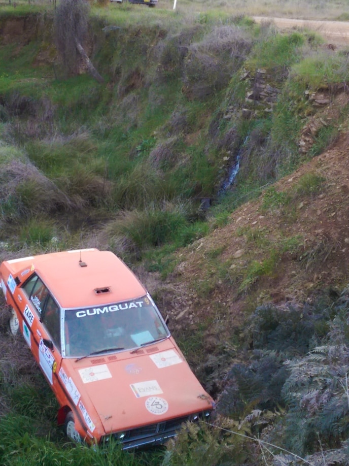 1980 Datsun rally car in ditch after rolling off an embankment.