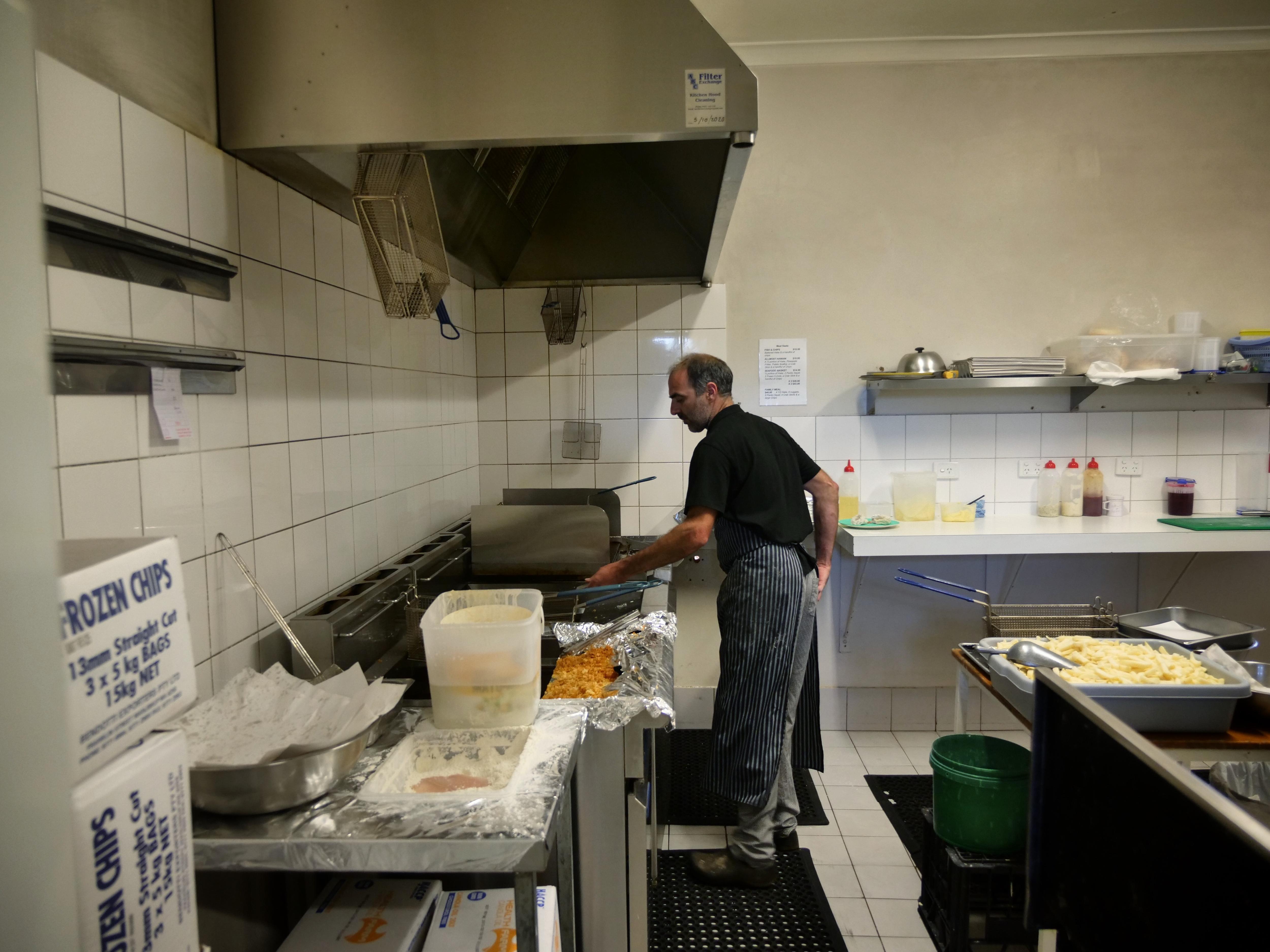 A man in a fish and chip shop frying food