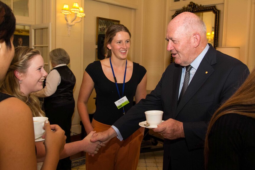 Sir Peter Cosgrove shakes hands with a young person.