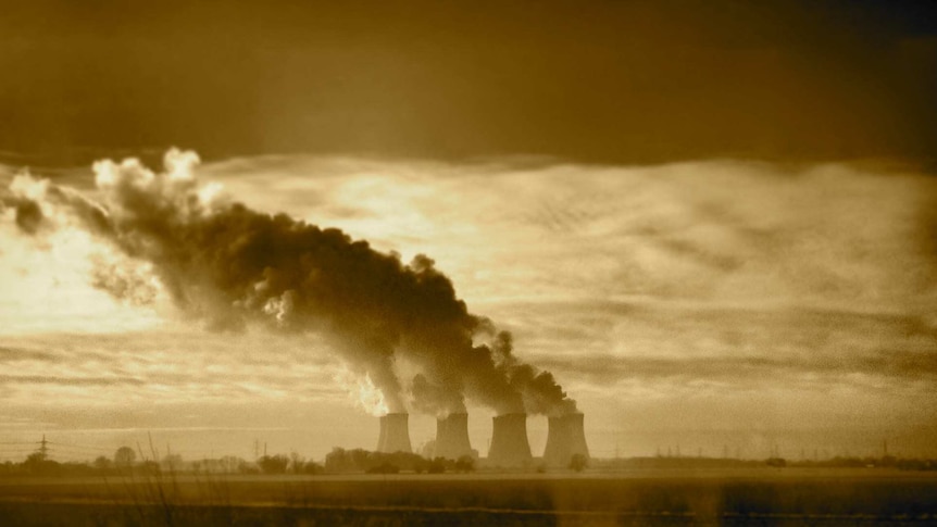 Four smoke stacks belch plumes of smoke into a overcast sky.