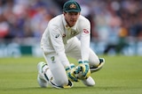 A wicketkeeper grimaces as he crouches after dropping a catch.