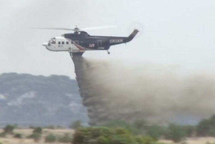 A water bombing aircraft drops liquid on a fire.