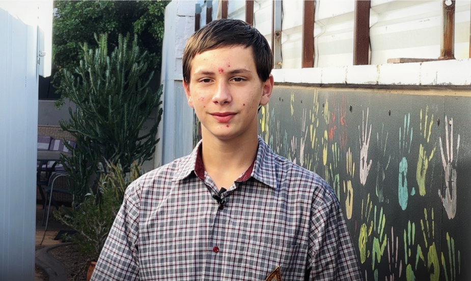 A young boy with brown hair and a red check shirt