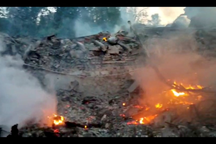 Burning debris scene at site of building hit by shelling.