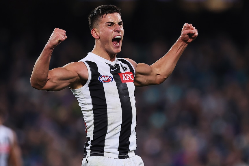 A Collingwood AFL player pumps his fists as he celebrates a goal.