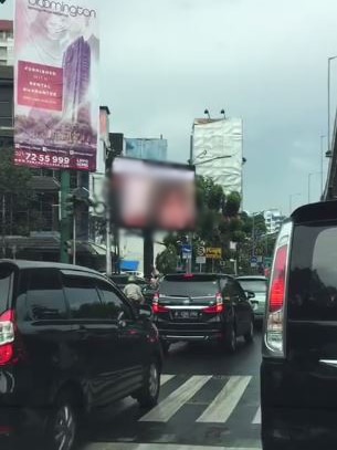 Cars lined up on the road where the billboard streams the video beside them