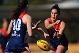 Melbourne Demons AFLW player Libby Birch has a look of concentration after executing a handball in a game