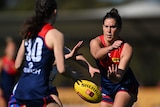 Melbourne Demons AFLW player Libby Birch has a look of concentration after executing a handball in a game