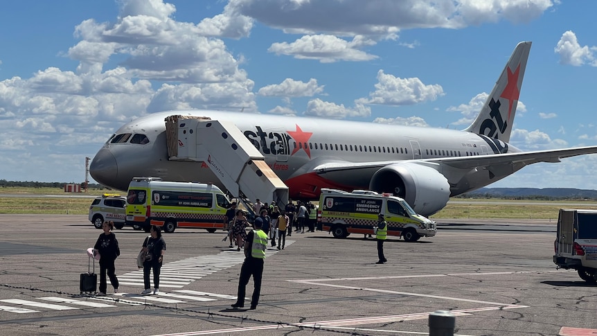 Passengers disembark from a jetstar plane as emergency crews park nearby at Alice Springs Airport