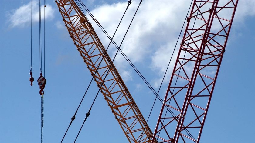 Two cranes swing past each other on a construction site