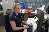A woman with a ponytail sitting at a computer