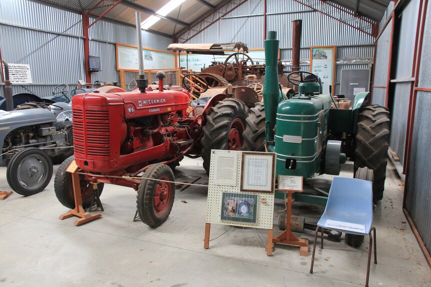 Two old tractors, one red, one green in the foreground of a tractor display