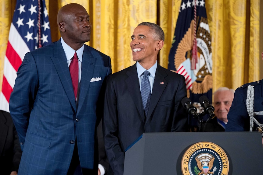 Basketballer Michael Jordan playfully looms to the left of Barack Obama.
