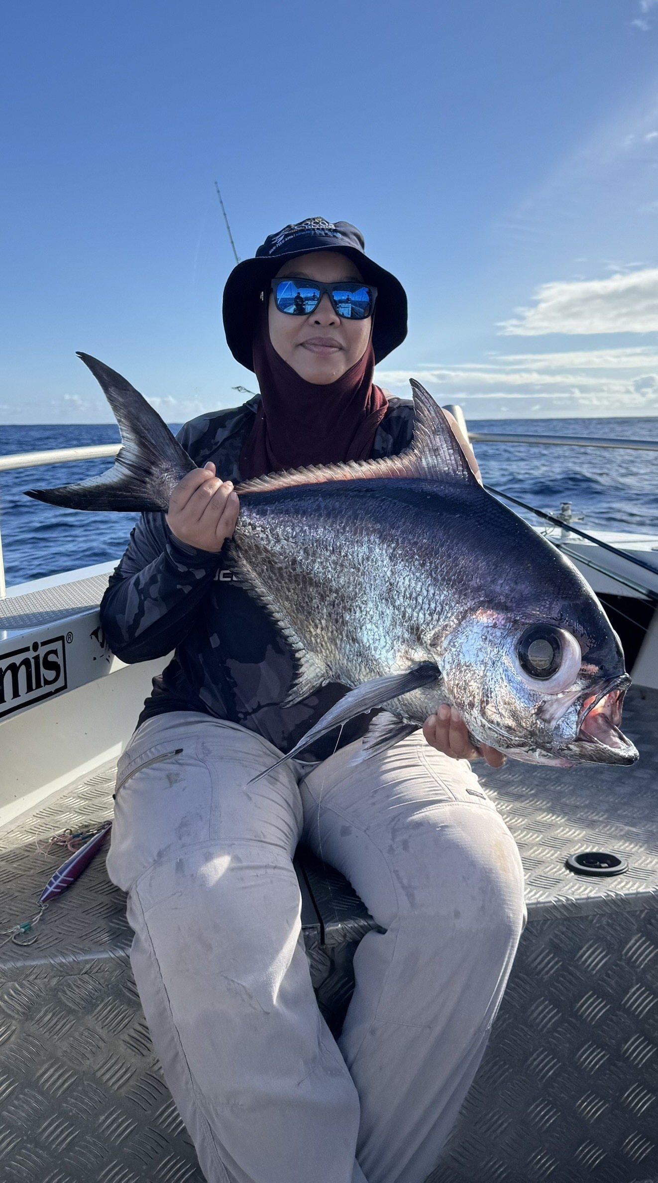 A picture of a woman on a boat holding a large fish