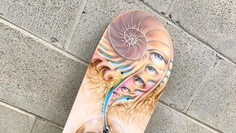 Airbrushed skateboard with skull and colourful eyes at the top.