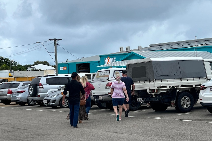 A group of five people walk in a carpark.