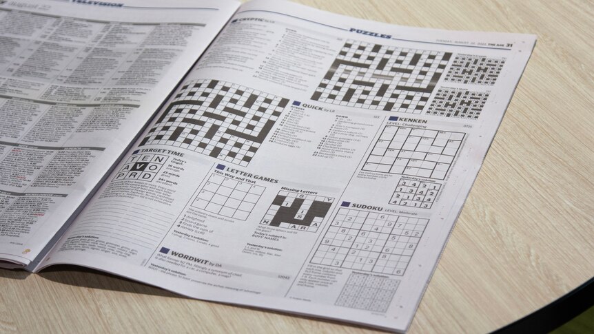 A newspaper open on the table at the puzzles page with no comics visible. 