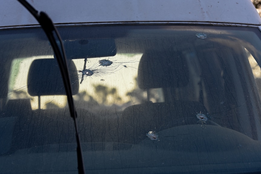 Bullet holes in the windshield of a car.