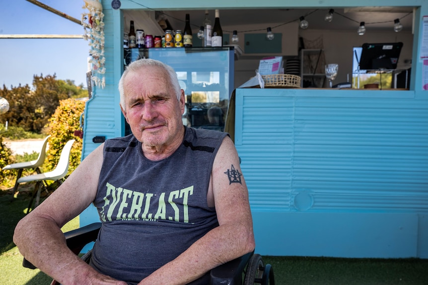 A man sits in front of a caravan food truck.